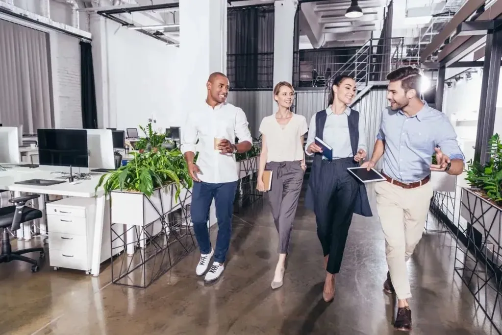 Four colleagues walking and talking through an open-plan office