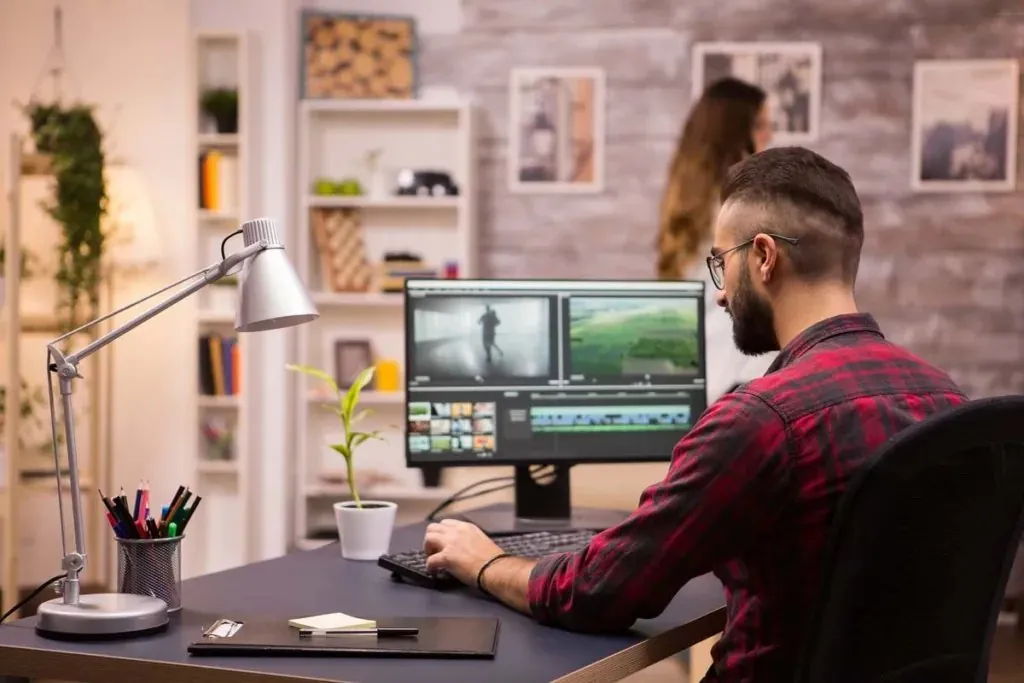 A video editor working on a timeline across two screens in a creative studio
