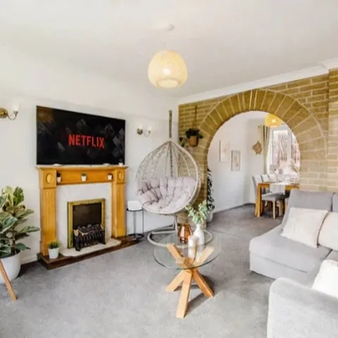 The living room of a Gold Key Property serviced accommodation home, with a brick archway, fireplace and hanging egg chair