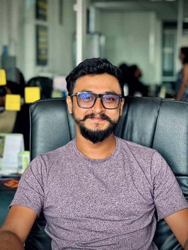 A team member in glasses relaxing in his chair in the office